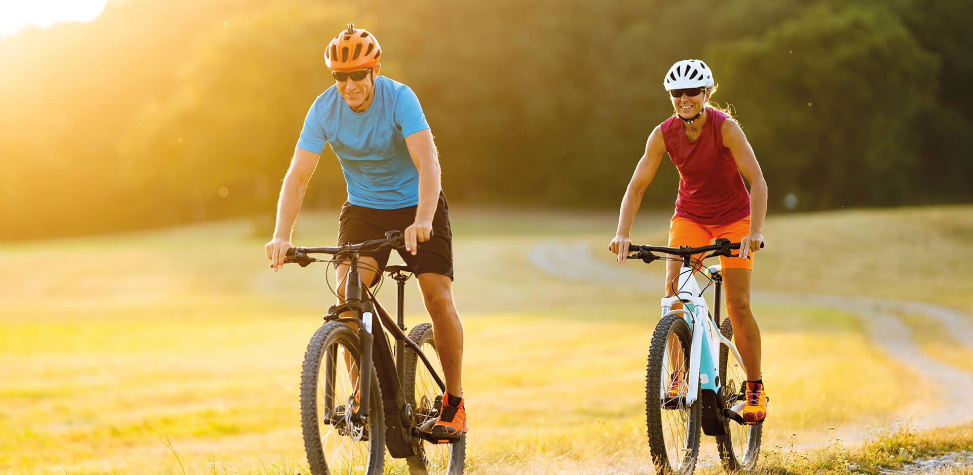 Zwei Personen fahren auf dem Fahrrad über ein Feld.